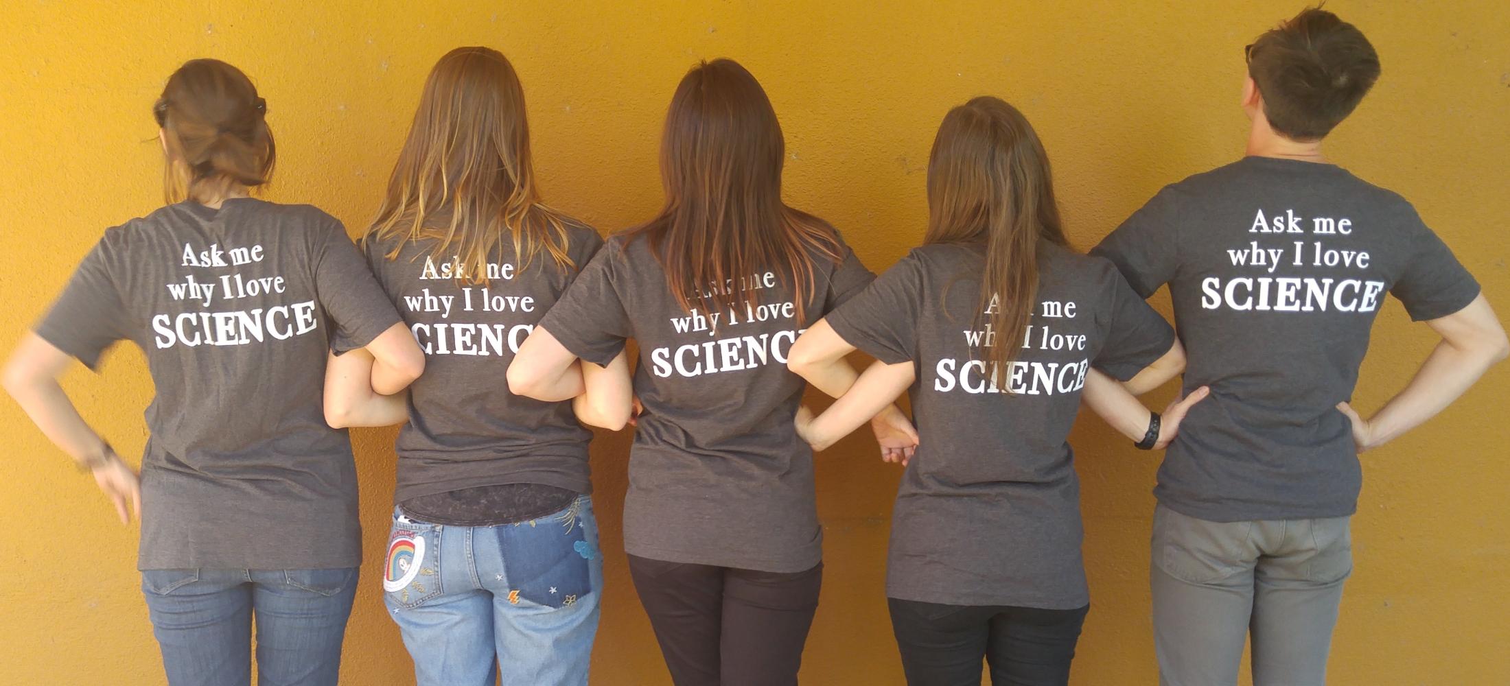 People with linked arms showing back of T-Shirt, which says "Ask Me Why I Love Science"