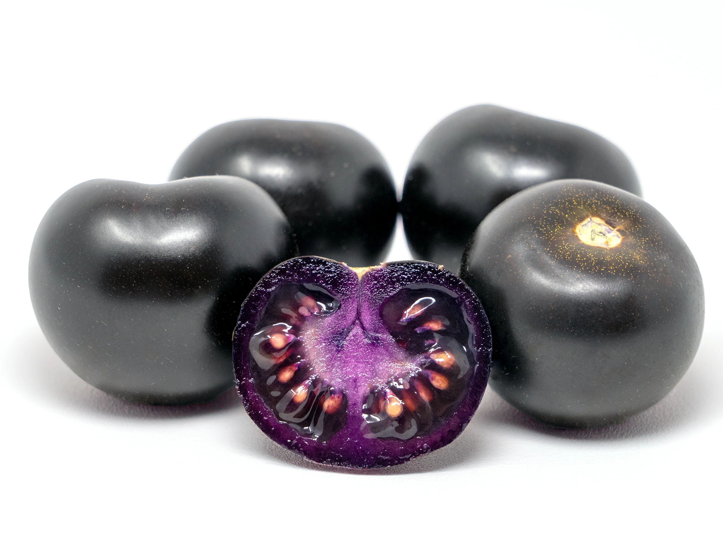 The Purple Tomato, sliced in half in the foreground showing the deep purple color throughout.