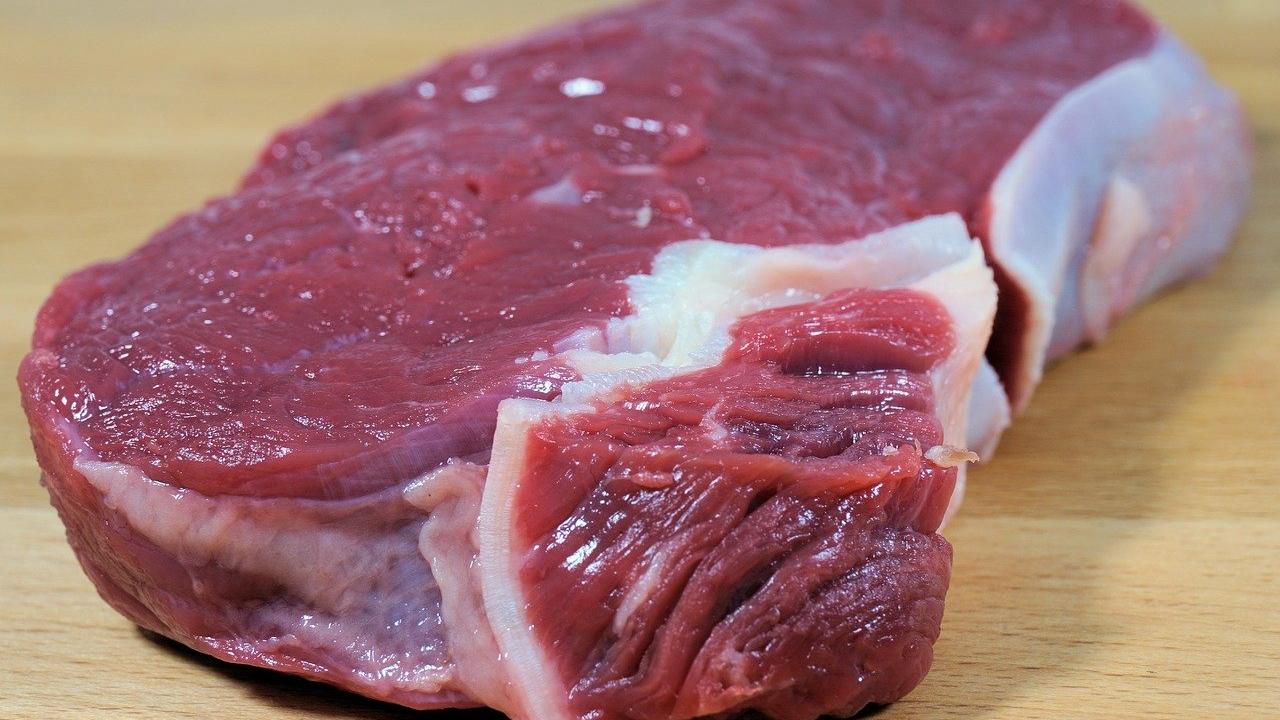 A piece of raw steak on a wooden surface.