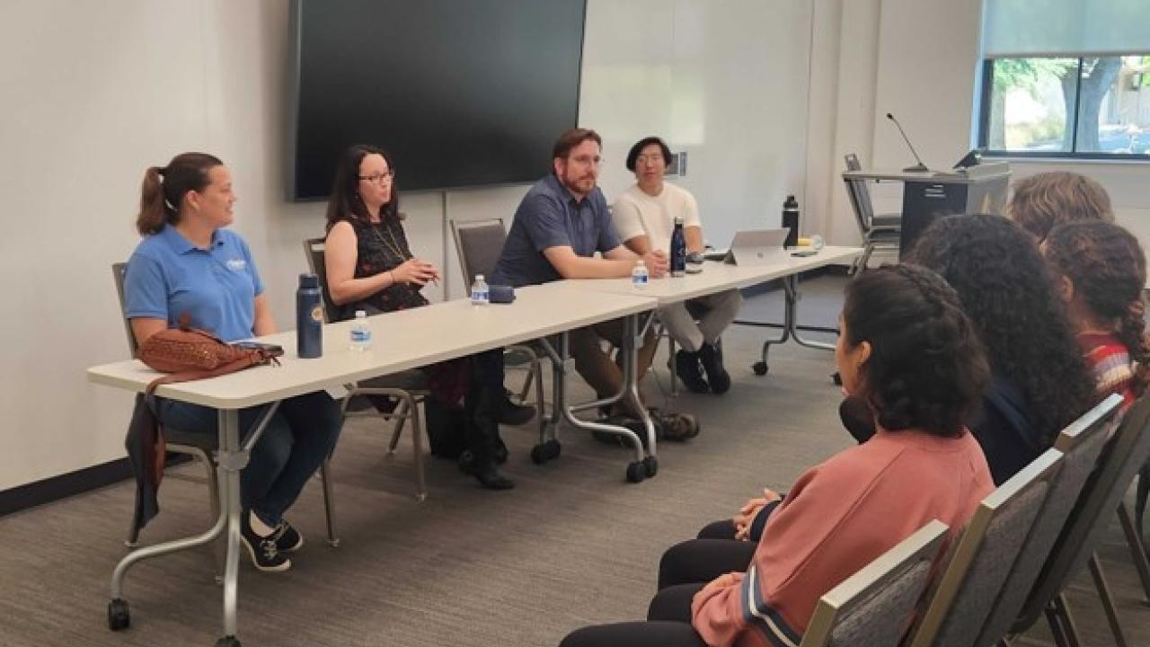 Four people sitting behind a table to represent a science policy panel