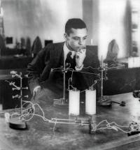 Dr. Ernest Just, sitting at a lab bench looking pensively at a 3D model. The photo is black-and-white.