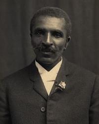 Black-and-white photograph of George Washington Carver. He is wearing a suit with a flower in the lapel.