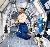 Dr. Mae Jemison is floating in a corridor of a space craft.