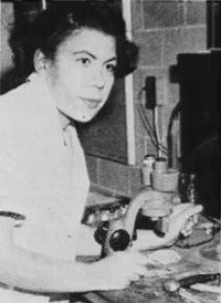 Black-and-white photograph of Dr. Margaret Strickland Collins. She is wearing a light colored blouse and is sitting in front of a microscope.