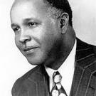 Dr. Percy Julian is looking to the left, wearing a striped suit and polka-dot tie. The picture is in black-and-white.